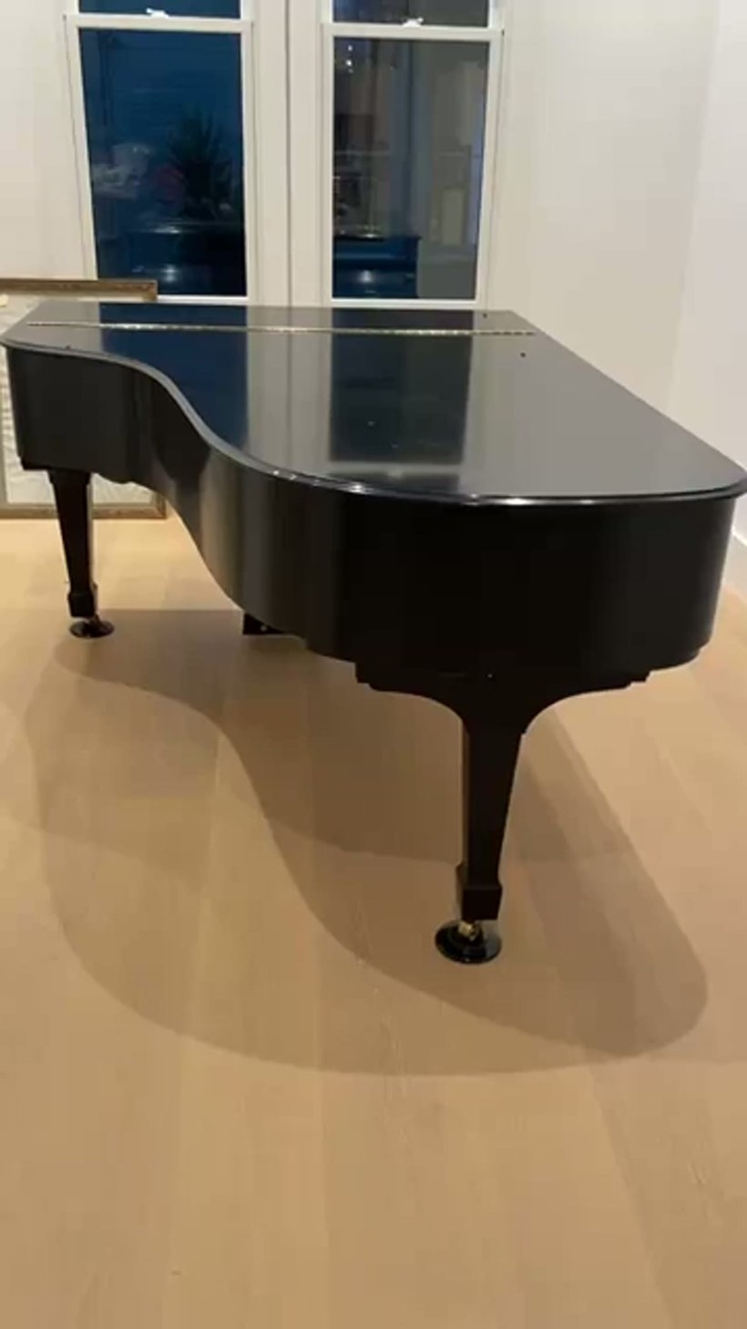 Movers easing a wrapped grand piano into a bright Rockland home