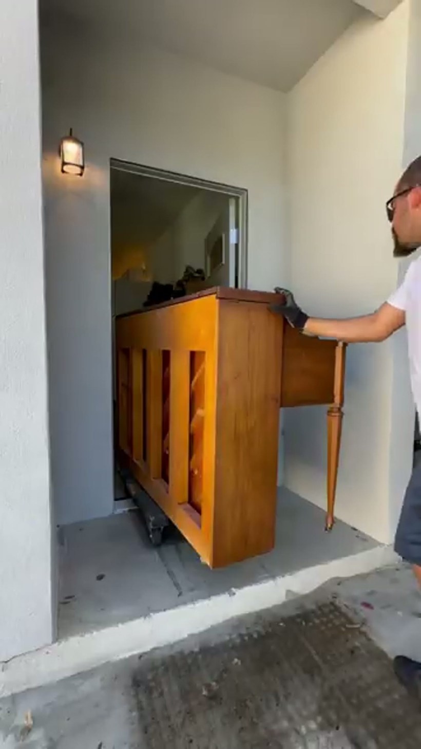 A mover taking a heavy safe up a flight of stairs on a stair dolly